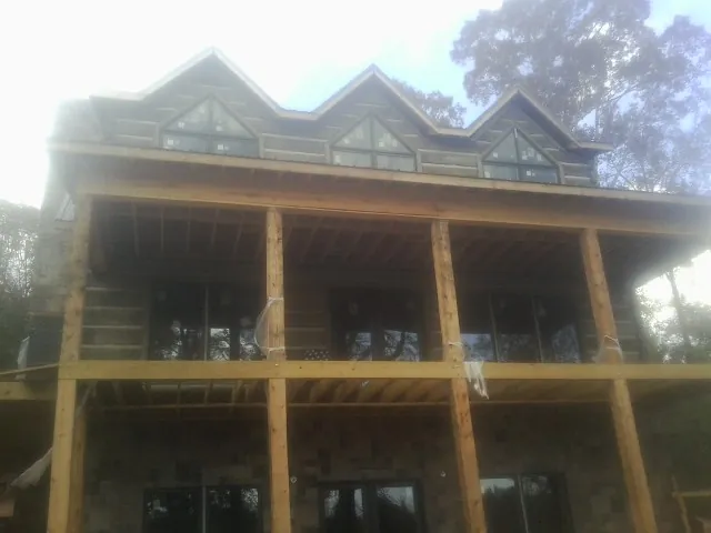 Dormers and porch framing on a large log home under construction — Roof Coating work by our crew in Highmount