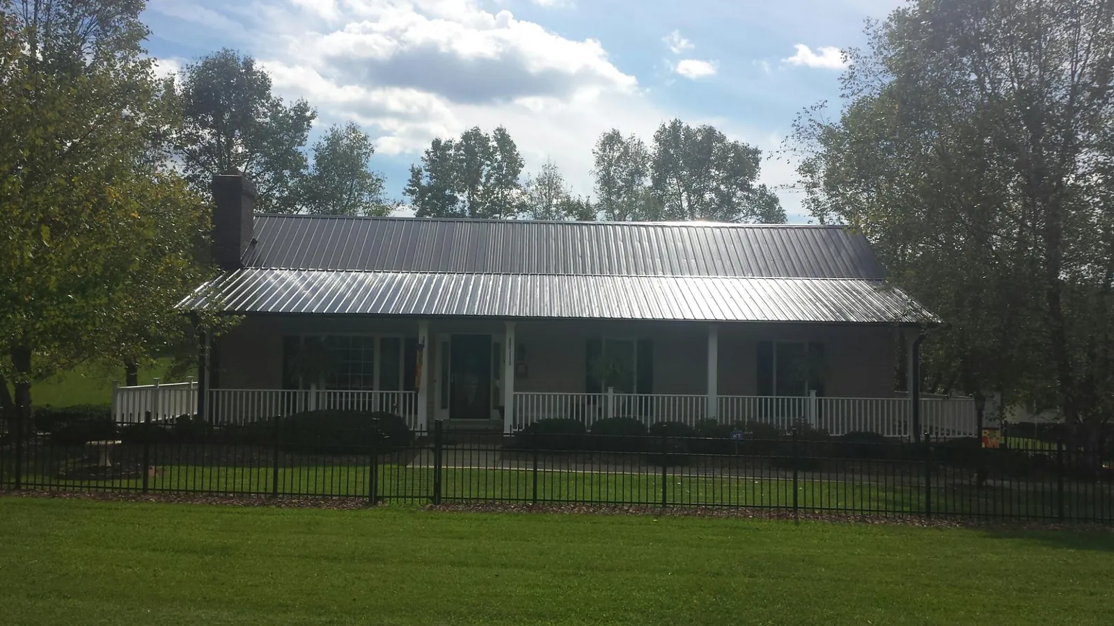 Gray metal roof on a brick ranch with a full width front porch — Gutter Guard Installation work by our crew in Highmount