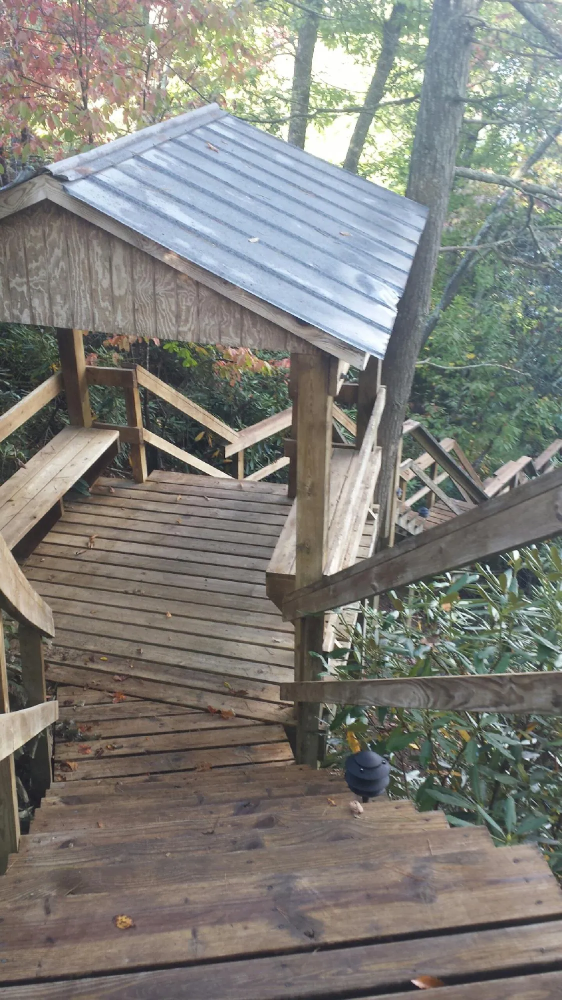 Metal roofed shelter over wooden steps on a wooded walkway — Skylight Repair & Installation work by our crew in Highmount
