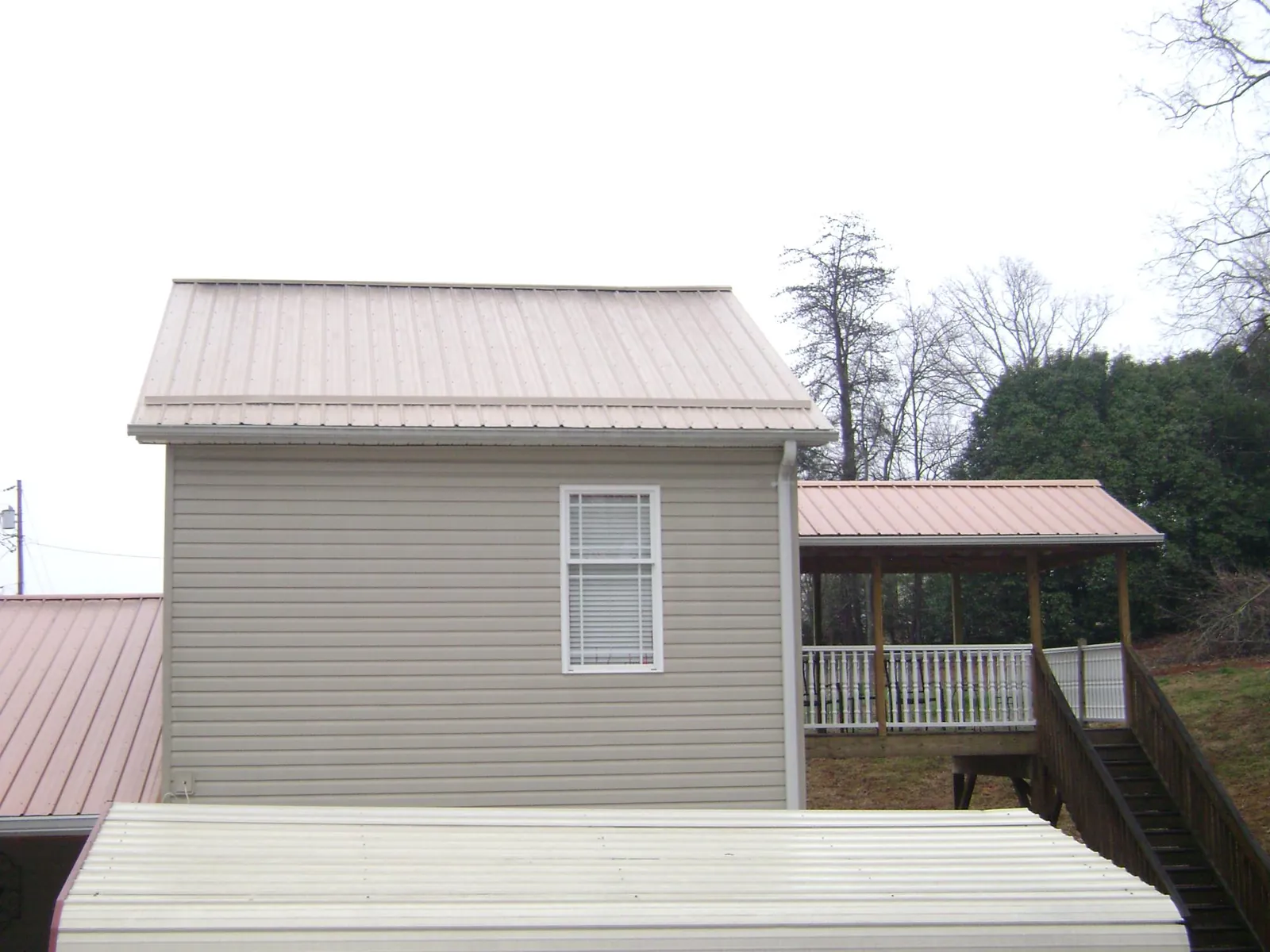 Tan metal roofs on a two story addition and attached porch, from a Roof Replacement job in Highmount