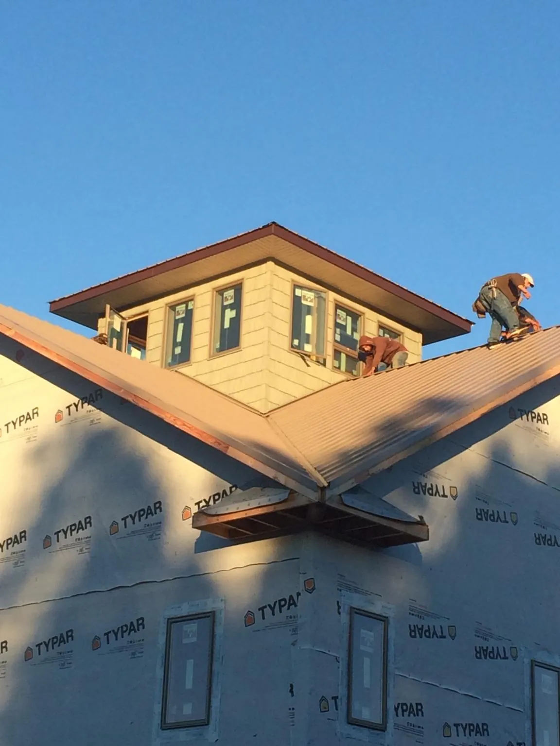 Roofers working around a rooftop cupola on a new metal roof at sunset — Roof Waterproofing in Highmount by Roofing Brothers